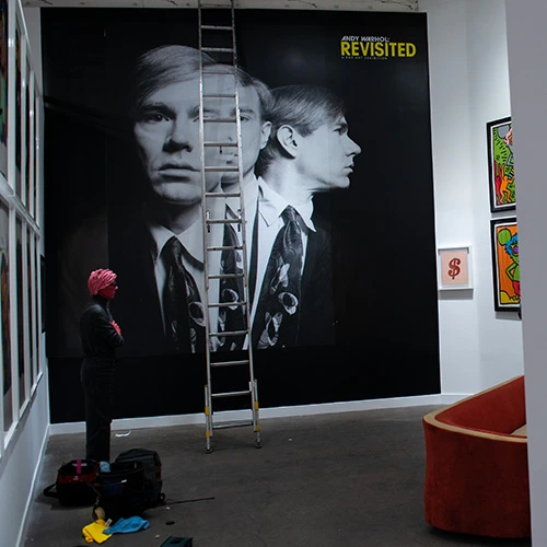 Large-scale Andy Warhol portrait wall graphic covering an entire wall in an art gallery, showcasing bold colors and striking contrasts typical of Warhol's pop art style